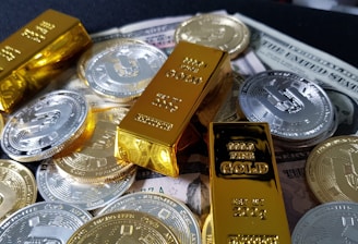 Several gold bars are placed on top of a pile of bitcoin coins and US dollar bills, indicating a scene of wealth and finance.