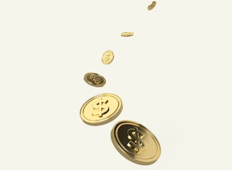 A sequence of golden coins with dollar signs is floating or falling diagonally across a light background. The coins appear shiny and metallic, suggesting wealth or financial growth.